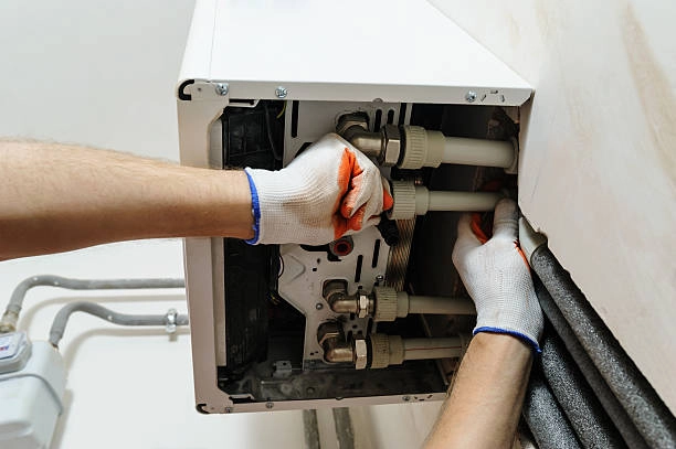 Technician repairing a wall-mounted water heater with protective gloves. -repair heating system