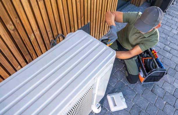 Technician repairing outdoor air conditioning unit, using tools and equipment. -heating repair service