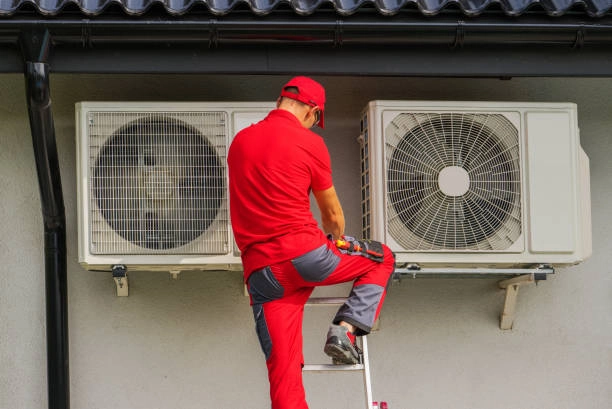 Technician installing heat pump unit on building exterior for cooling. -install heat pump