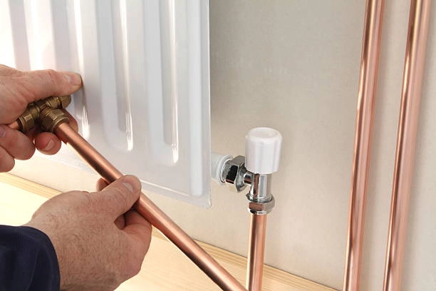 Connecting copper pipes to a radiator for heating system installation. -heater installation