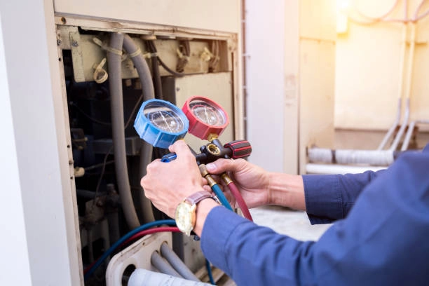 Technician using pressure gauges to check HVAC system during maintenance. -heating installation