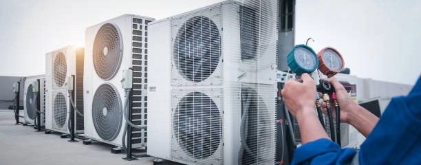 Technician measuring air conditioning pressure on rooftop HVAC units outdoors. -ac repair company